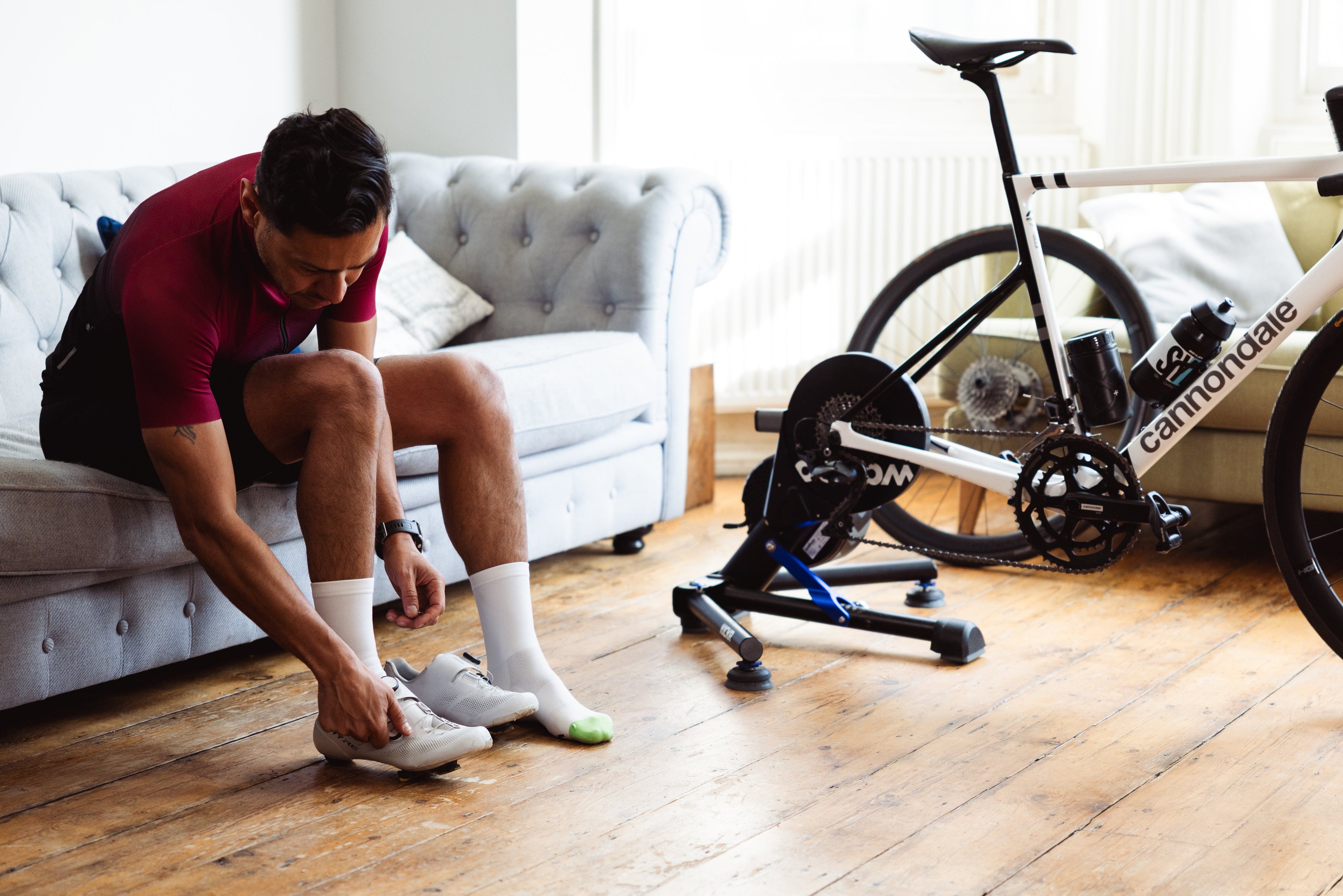 Rider prepares for a turbo session by putting on Veto white cycling socks